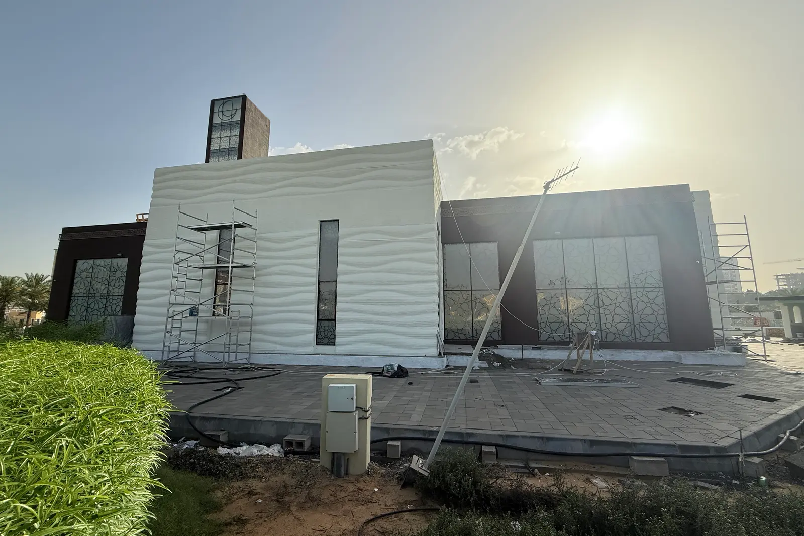 The 3D-printed mosque during construction, scaffolding still against the wave-textured printed walls